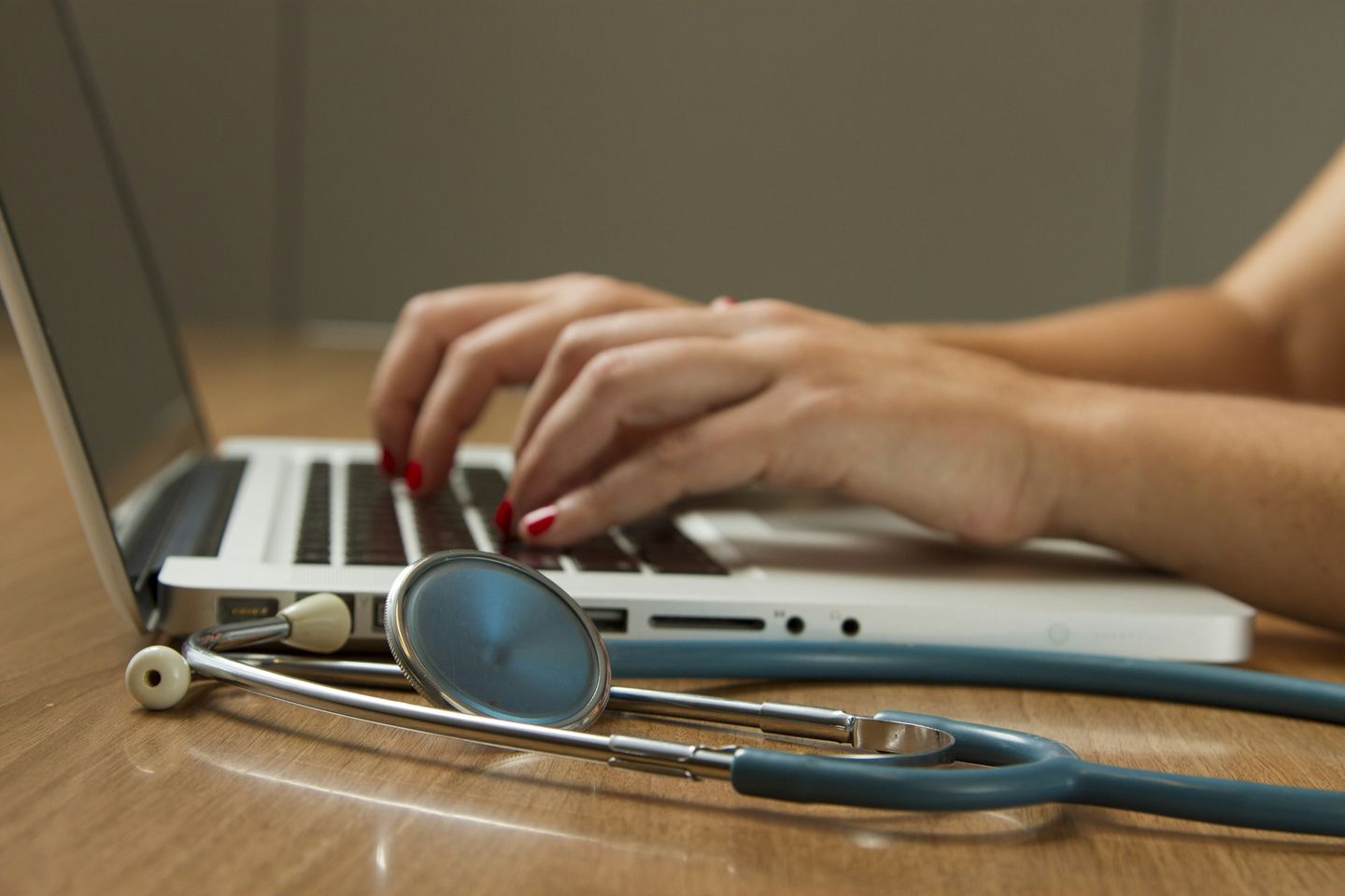 A stethoscope resting beside a clinician's laptop.