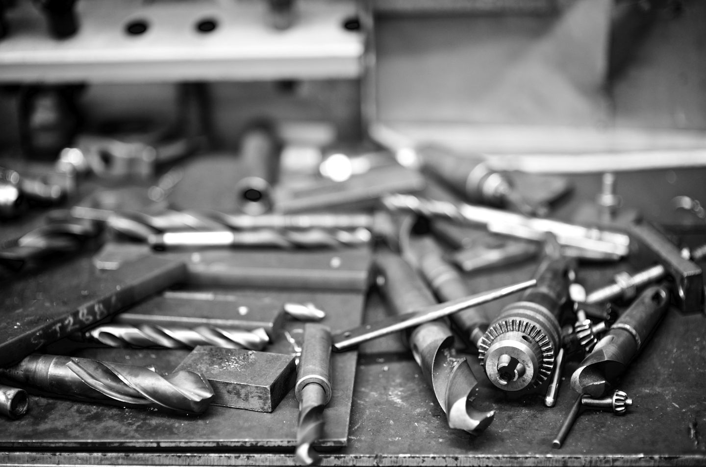 Drill bits and metalworking tools spread across a workshop bench.
