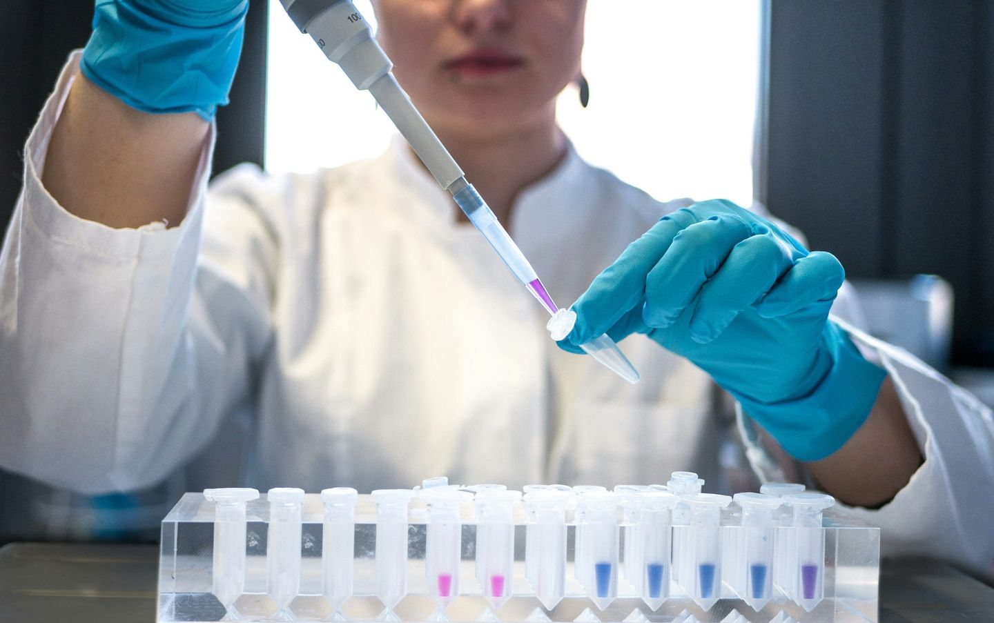 A laboratory scientist pipetting a sample into a test tube.